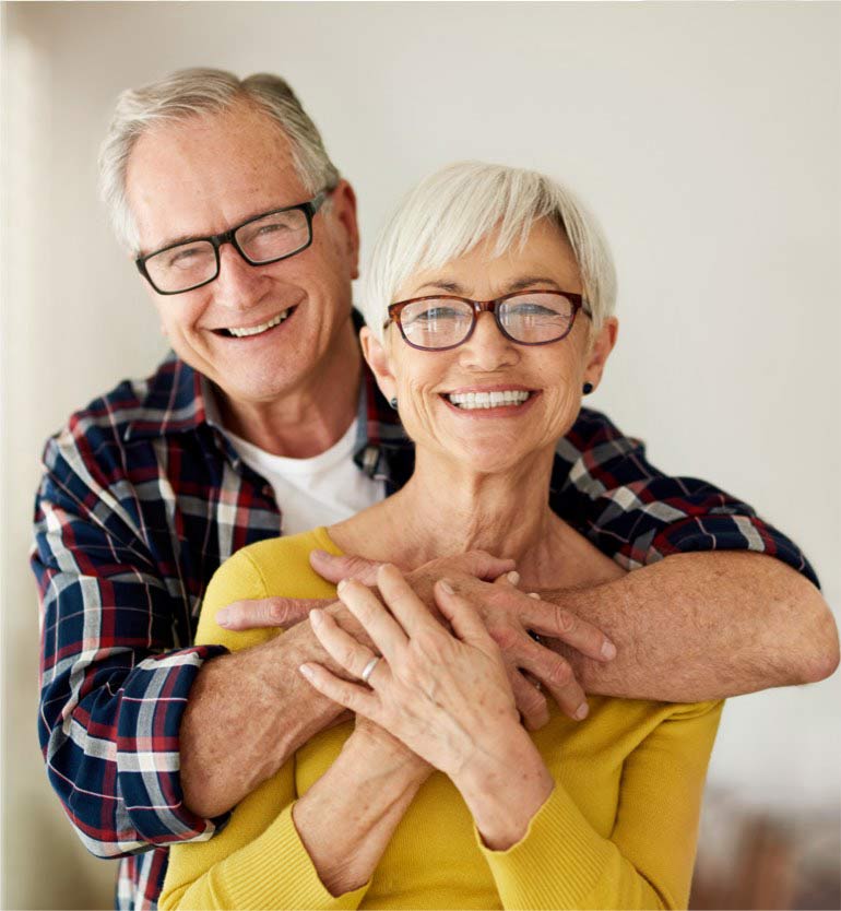 Happy senior couple smiling joyfully while embracing each other indoors
